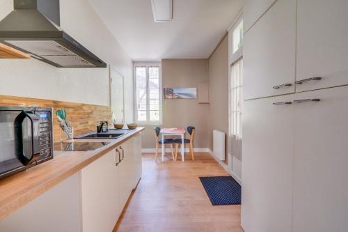 - une cuisine avec des placards blancs, un évier et une table dans l'établissement Studio O Calme, à Arcachon
