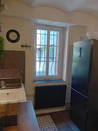 Il comprend une cuisine équipée d'un réfrigérateur et d'une fenêtre. dans l'établissement Appartement charmant à Alès | 62 m² | Piscine privée, à Alès