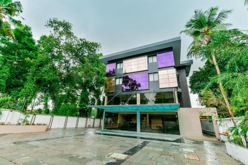 a building with purple windows and palm trees at Townhouse Edassery Blue Bells in Cochin