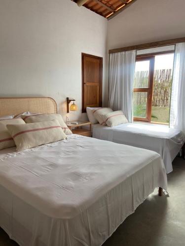 a bedroom with two beds and a window at Casa Teçá in Guriú