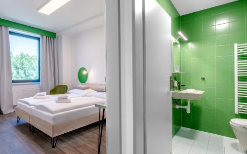 a bedroom with a bed and a bathroom with green tiles at Hotel Active Stadium in Lovosice