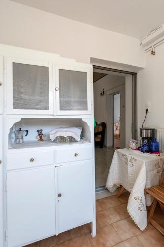 a white cabinet in a kitchen with a table at Grandma's House Mani in Plátanos
