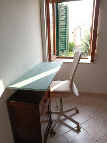 a desk with a chair in front of a window at la casetta toscana in Peccioli