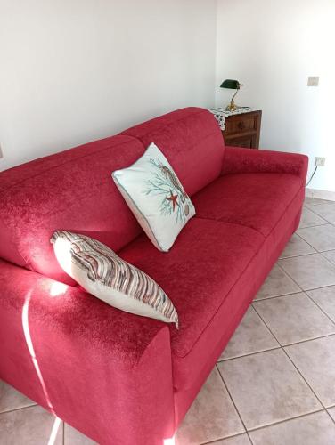 a red couch with two pillows on it at la casetta toscana in Peccioli