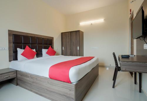 a bedroom with a large bed and a desk at Super Hotel O Gokul Grand Near SR Nagar Police Station in Hyderabad