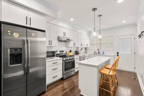 a kitchen with white cabinets and a stainless steel refrigerator at Federal Hill Luxury with Parking & Harbor View Rooftop in Fells Point