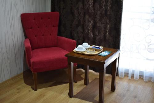 a red chair and a wooden table with a red chair and a table with at Bayazıt Hotel in İskenderun