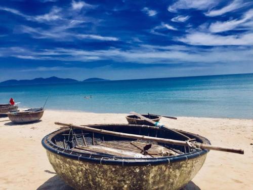 a wooden boat sitting on a sandy beach at La Belle An Bang Seaside Hideaway in Hoi An