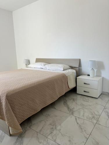 ein weißes Schlafzimmer mit einem Bett und einem weißen Nachttisch in der Unterkunft Faxxina in Is-Swieqi