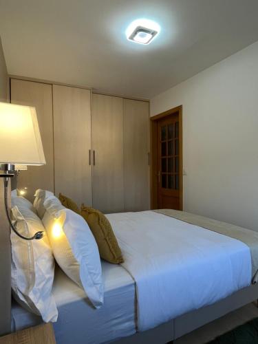 a bedroom with a large white bed with a lamp at AppartHôtel Elite Spa in Forbach