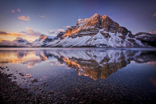 a mountain with its reflection in the water at The Lodge at Bow Lake in Lake Louise