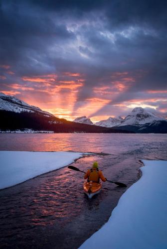 a person in a kayak in the water at sunset at The Lodge at Bow Lake in Lake Louise