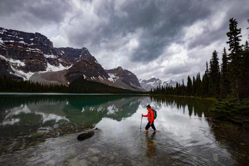 a person walking across a body of water at The Lodge at Bow Lake in Lake Louise