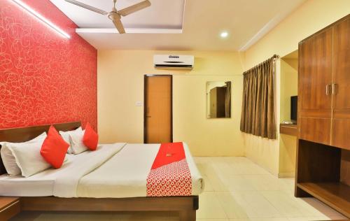 a bedroom with a bed with a red wall at Hotel O Sunrise in Vadodara