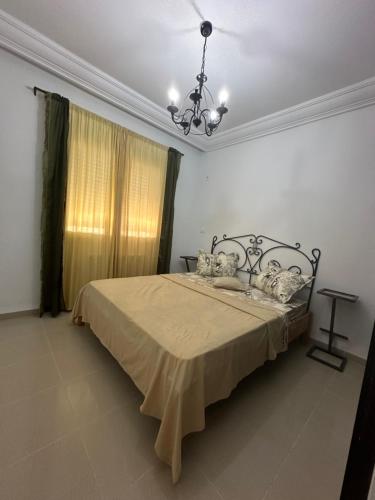 een slaapkamer met een bed met een kroonluchter bij S1 vue de mer in Chott Meriem
