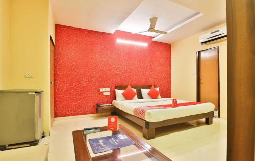 a bedroom with a bed and a red wall at Hotel O Sunrise in Vadodara