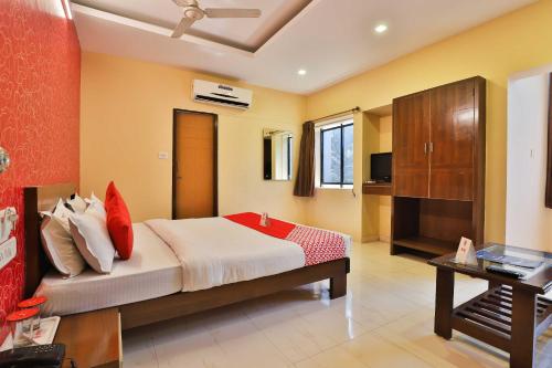 a bedroom with a large bed with red pillows at Hotel O Sunrise in Vadodara