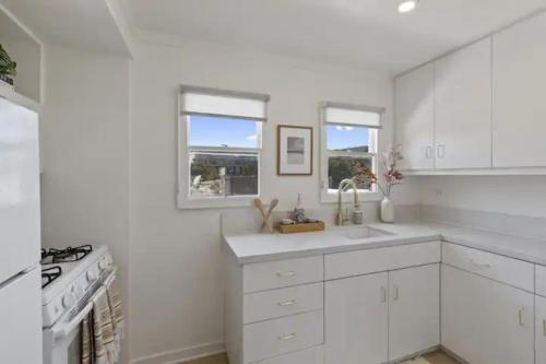 a white kitchen with a sink and a stove at Cozy 1 BR Casita Overflowing with Natural Light in San Diego