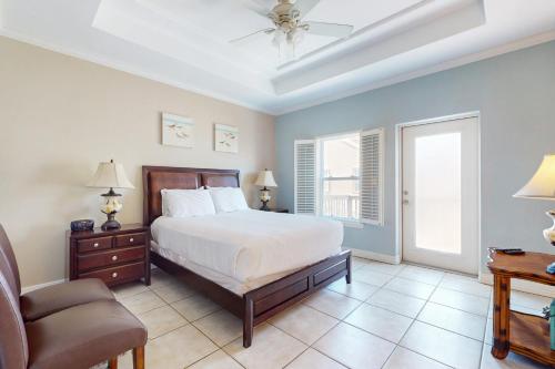 a bedroom with a bed and a chair and a window at Garden Breeze Condominiums #3 in South Padre Island