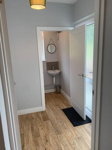 a hallway with a bathroom with a sink and a toilet at Cheddar Head Bungalow in Rodney Stoke