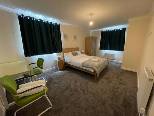 a bedroom with a bed and a green chair at The Iris house is close to city centre and is ideal for tourists, visiting family members or work related activities including contractors in Peterborough