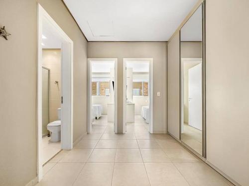 a bathroom with three mirrors and a toilet and sinks at Piscina Privativa - Condominio - Churrasqueira - Espaçosa in Guarujá