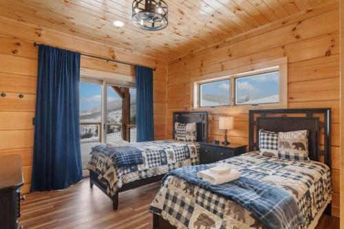 2 letti in una camera con pareti e finestre in legno di Big Sky Cabin at Monteagle a Banner Elk