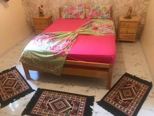 a bed with four rugs on the floor in a room at Résidence Choco in Tabarka