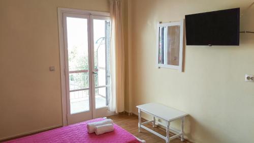 a bedroom with a pink bed and a window at Nikolas Studios in Moraitika