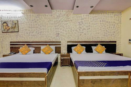 two twin beds in a room with a wall at Spot On Swagat Palace in New Delhi