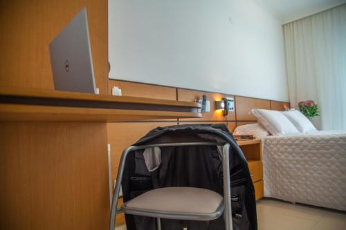 a small room with a chair and a bed at Atlantico Inn Apart Hotel in Santos