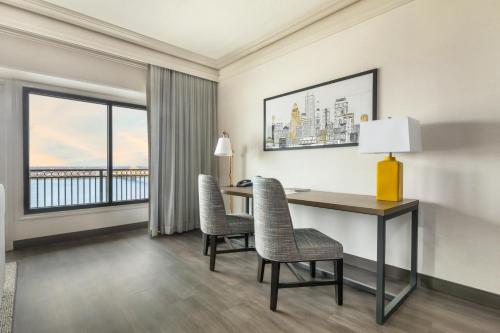 a hotel room with a desk and chairs and windows at Galt House Hotel, A Trademark Collection Hotel in Louisville