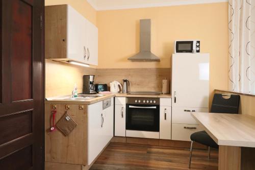 a small kitchen with white cabinets and a refrigerator at Villa Liliengrund in Eisenach