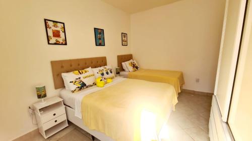 a bedroom with two beds with yellow sheets at Cantinho da Bell in Araruama