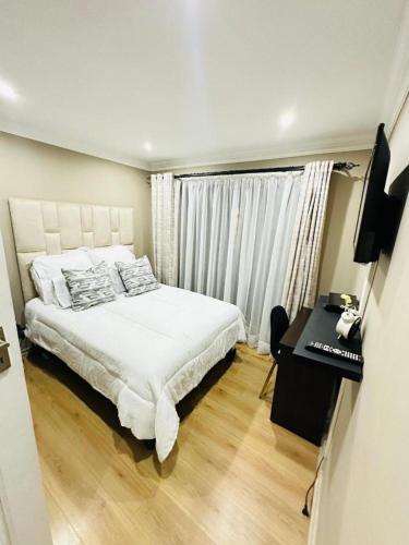 a bedroom with a bed and a desk and a television at Mayberry Heights in Alberton