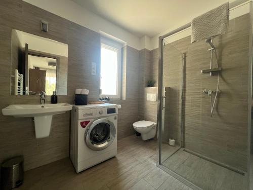 a bathroom with a washing machine and a sink at Sophia Apartman Gödöllő in Gödöllő