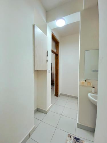 a white bathroom with a sink and a mirror at Bahari Three Bedroom Mombasa in Mombasa