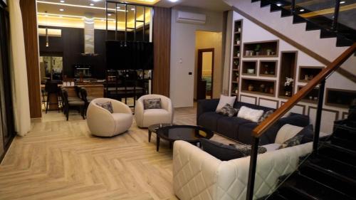 a living room with couches and chairs and a staircase at Kinda vip in Al Mashāriqah