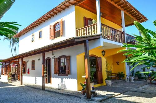 a yellow and white house with a balcony at Viva Brasil Pousada in Paraty