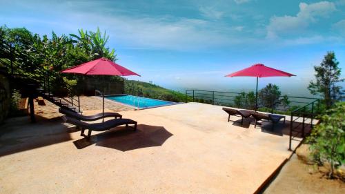 a patio with two chairs and two umbrellas at Vantage hills Haputale in Haputale