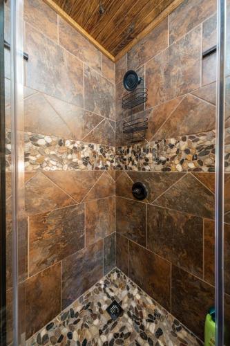 a bathroom with a shower with brown tiles at River Lodge Escape with Hot Tub in Glenwood