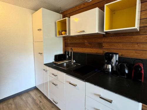 une cuisine avec des armoires blanches et un évier dans l'établissement Résidence Carene - 2 Pièces pour 4 Personnes 23, à Mâcot La Plagne
