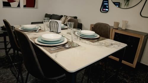 a dining room table with plates and glasses on it at Residenciales H1 & H2 - Breakfast & Room Service - Airport close in Santiago de los Caballeros