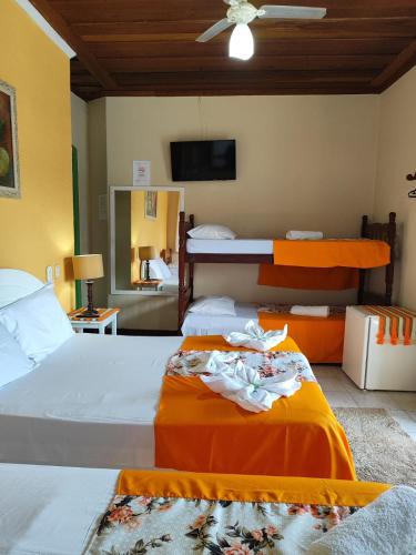 a bedroom with two beds and a flat screen tv at Pousada Florescer in Paraty