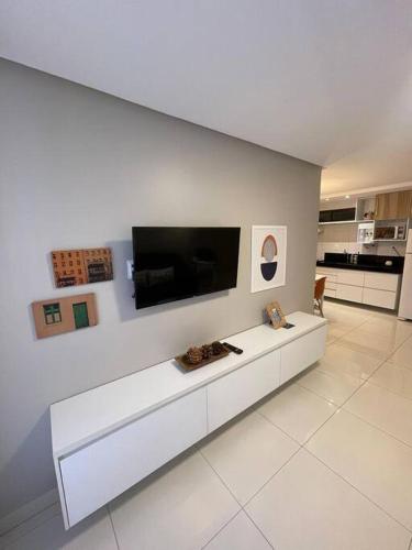 a living room with a tv on a white wall at Urbani Smart Flat - by Jess in Tambaú