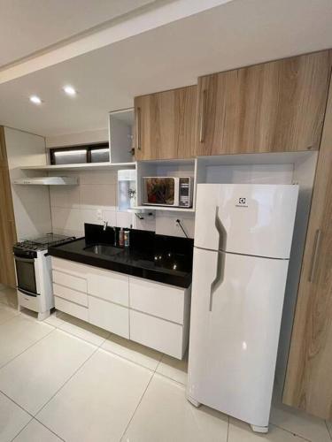 a kitchen with a white refrigerator and a stove at Urbani Smart Flat - by Jess in Tambaú