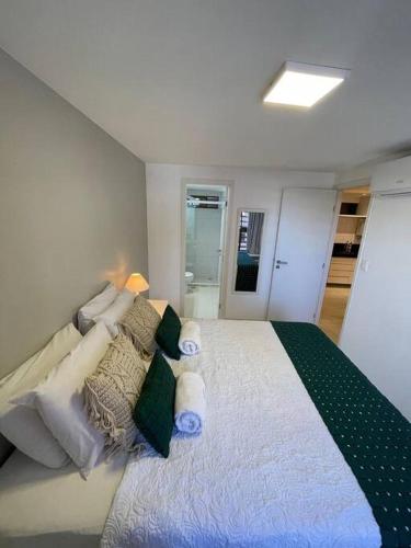 a white bedroom with a large bed with pillows at Urbani Smart Flat - by Jess in Tambaú