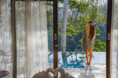 a woman standing outside of a door looking outside at The Hidden Paradise Ubud - CHSE Certified in Ubud