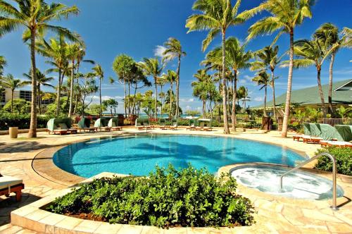 a swimming pool with palm trees and chairs in a resort at Villa 317 at Turtle Bay in Kahuku