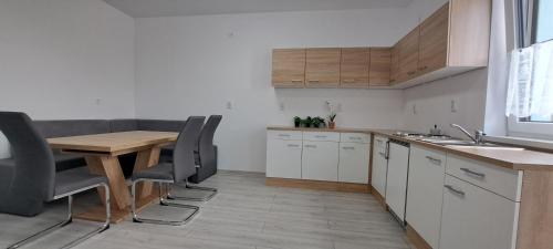 a kitchen with white cabinets and a wooden table and chairs at Haus MaryLu in Knetzersdorf